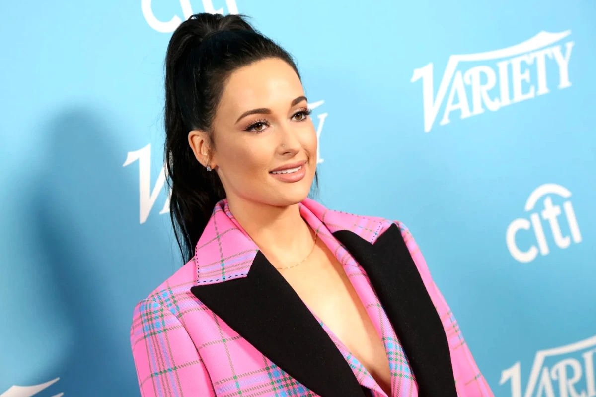Demi Lovato et Kesha posent côte à côte, souriantes, sur fond sombre lors d’un événement public