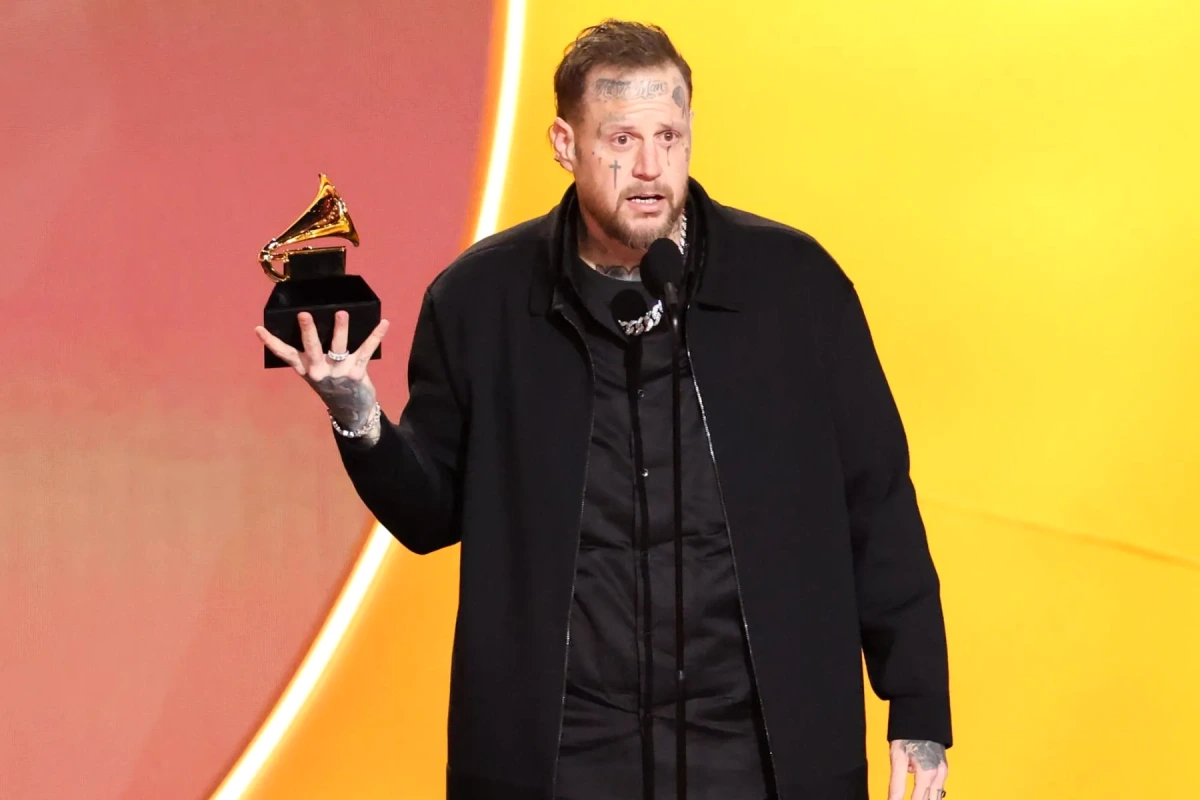 Jelly Roll sur scène, micro en main, portant une veste sombre, éclairé par des projecteurs colorés