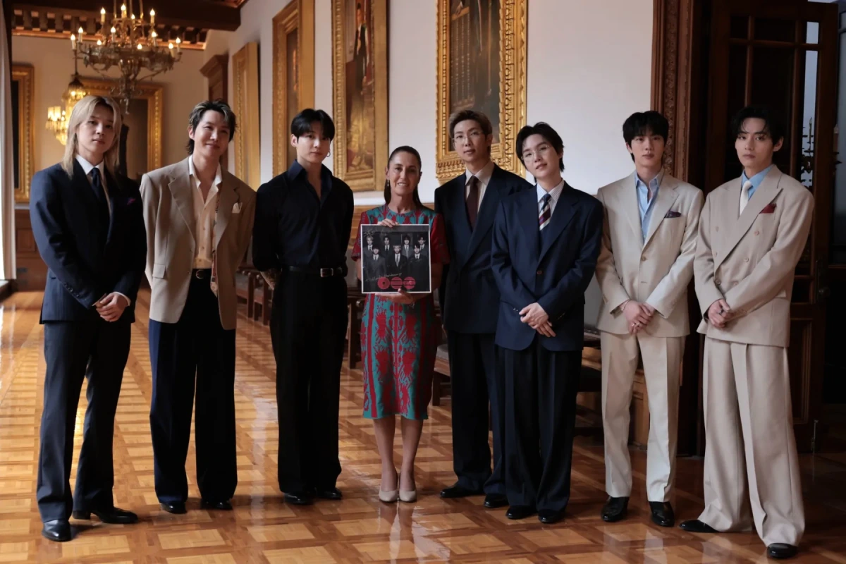 BTS posant devant le Palais national du Mexique, avec la façade historique et des touristes en arrière-plan