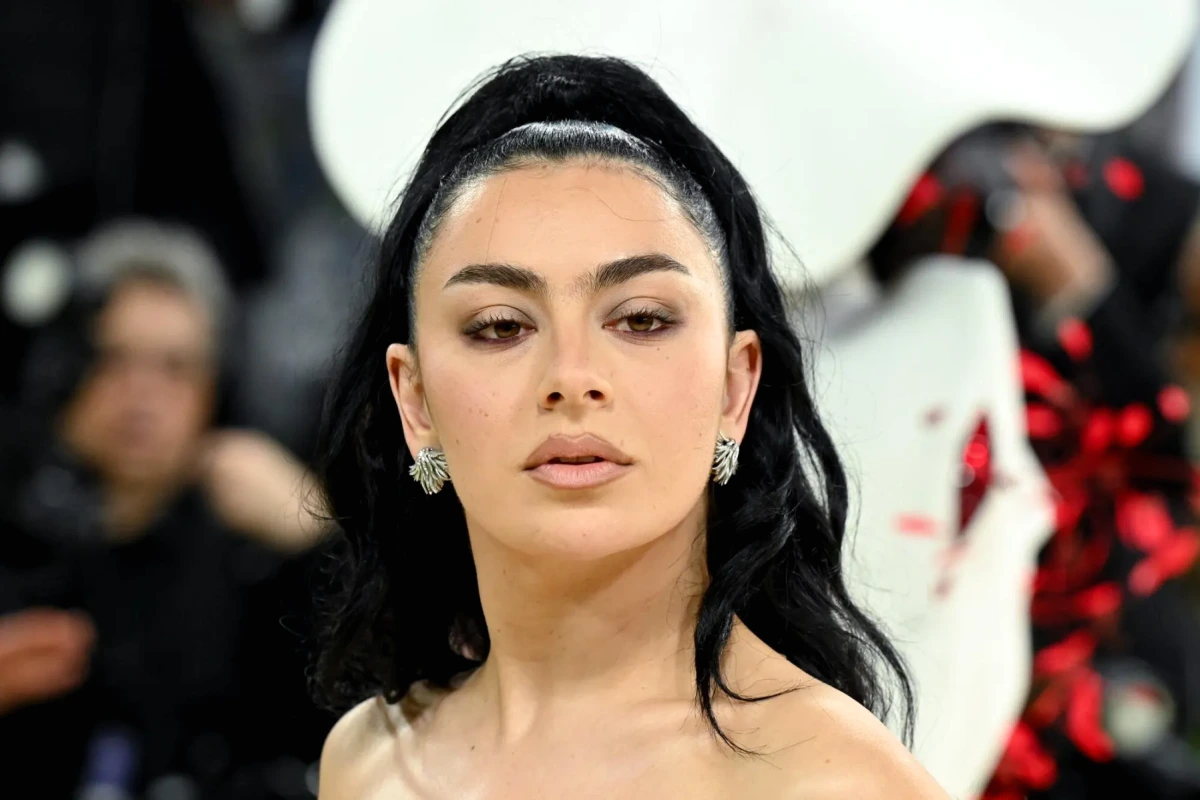 Charli xcx sur scène, fracassant une guitare électrique, micro à la main sous des projecteurs colorés
