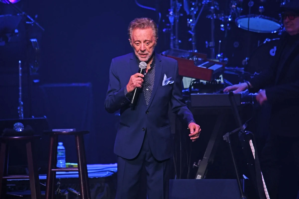 Frankie Valli sur scène au micro, sous des projecteurs, lors d’un concert de sa tournée 2026