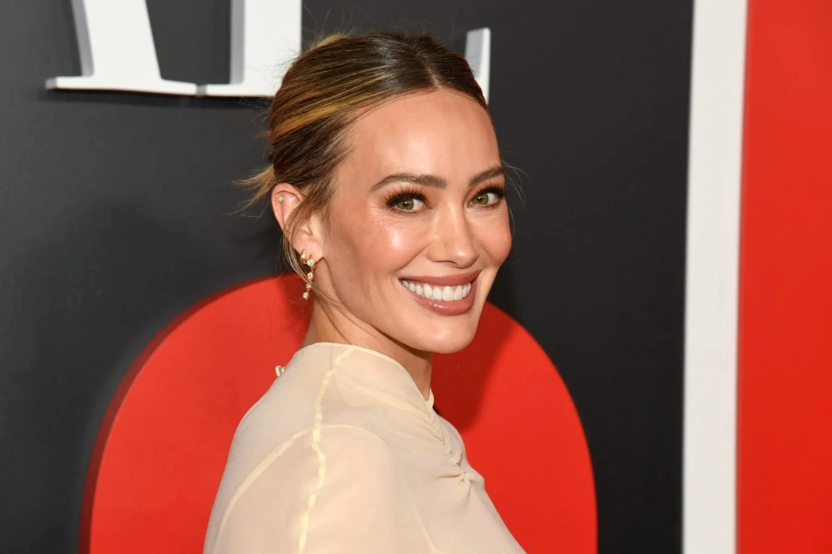 Hilary Duff en maillot de bain, posant pour Sports Illustrated Swimsuit sur une plage ensoleillée.
