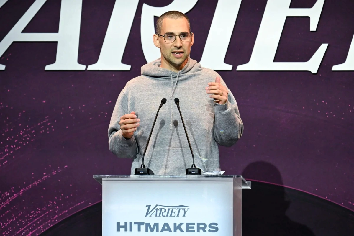 Jack Antonoff sur scène, micro en main, sous des projecteurs, devant un fond sombre et flou