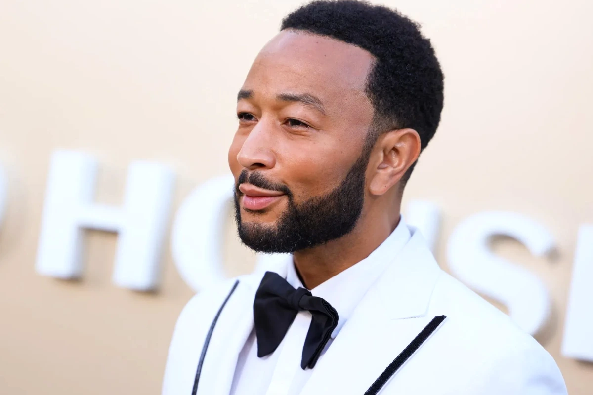 John Legend sur scène avec micro, éclairages bleus et public flou, lors d’un concert au Lincoln Center
