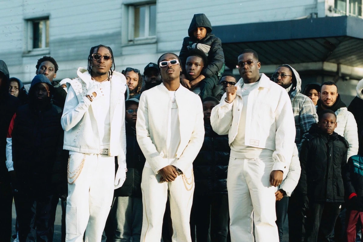 Membres d’un groupe de rap français sur scène, micros en main, éclairés par des projecteurs colorés