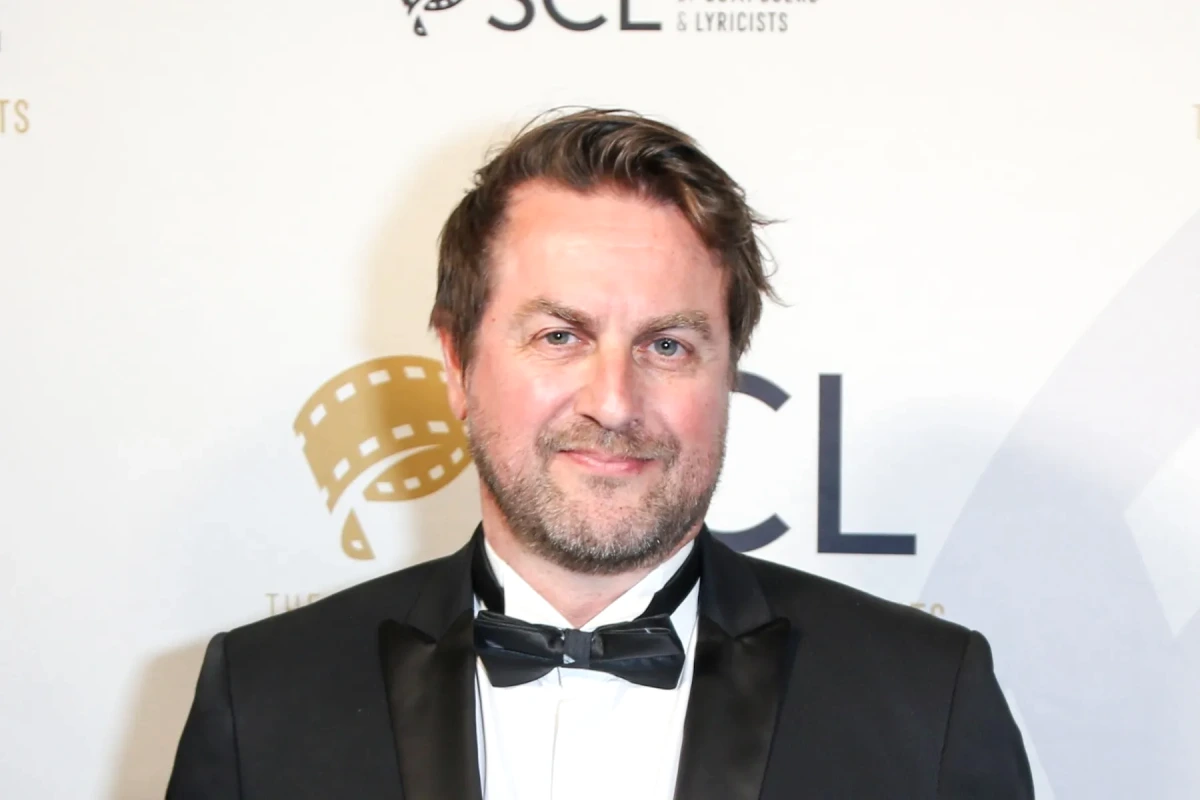 Portrait de Mark Smythe en costume sombre, souriant, avec un fond flou de Los Angeles en arrière-plan