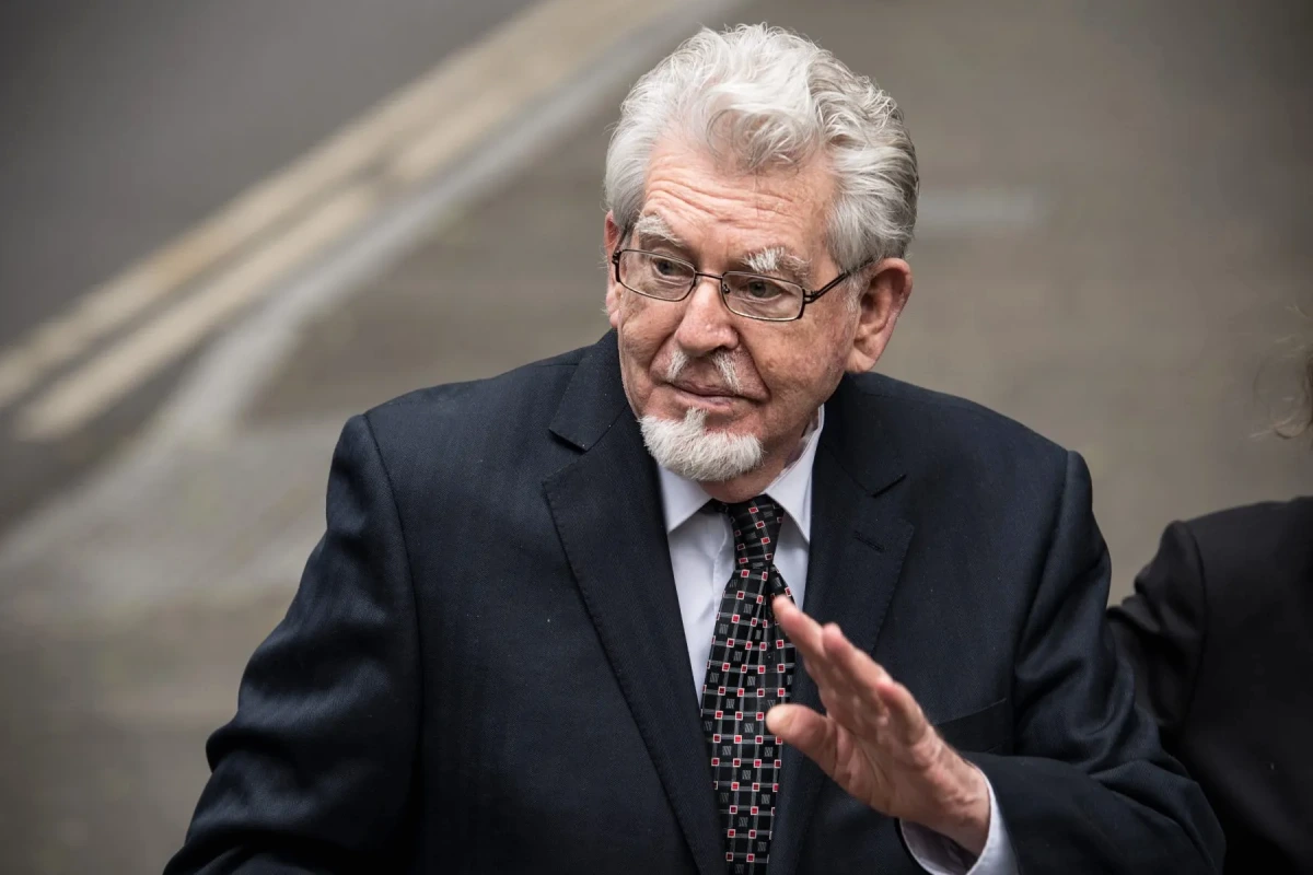 Portrait de Rolf Harris en gros plan, éclairage sombre, avec le titre « Primetime Predator » en arrière-plan