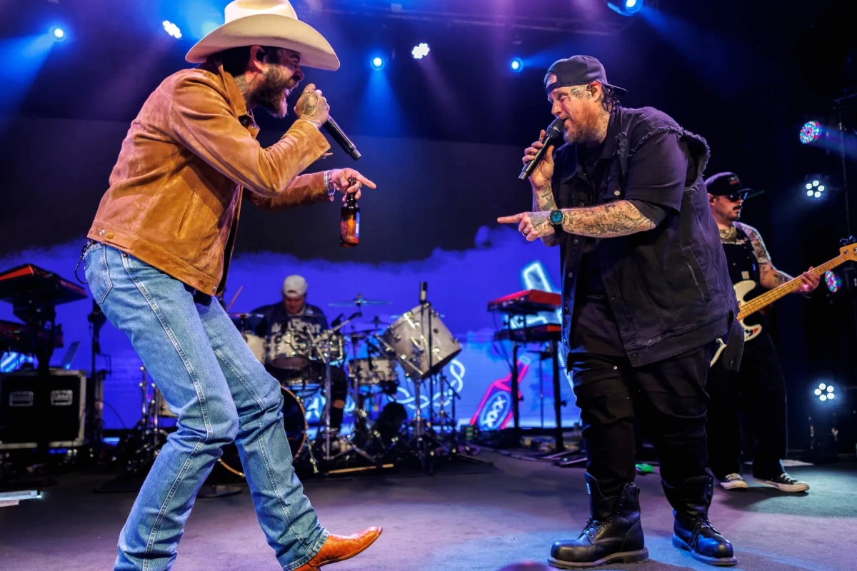 Post Malone sur scène, micro à la main, sous des projecteurs colorés, devant un public en concert