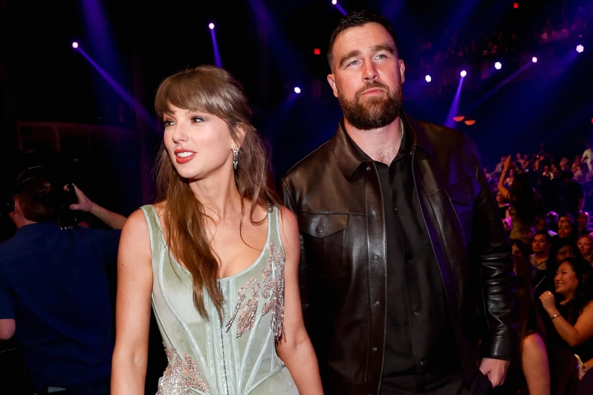 Travis Kelce et Taylor Swift posent côte à côte sur un tapis rouge, souriants devant les flashs.