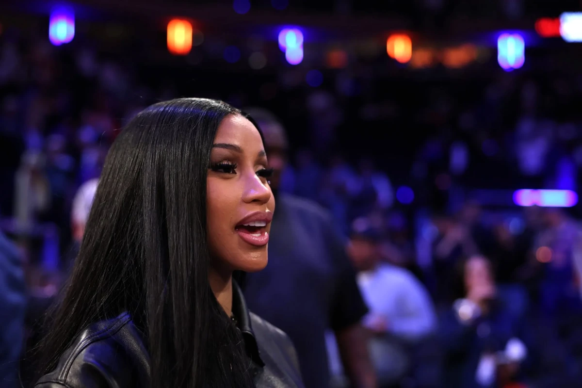 Cardi B en tenue de scène, micro en main, devant un décor évoquant New York et les Knicks
