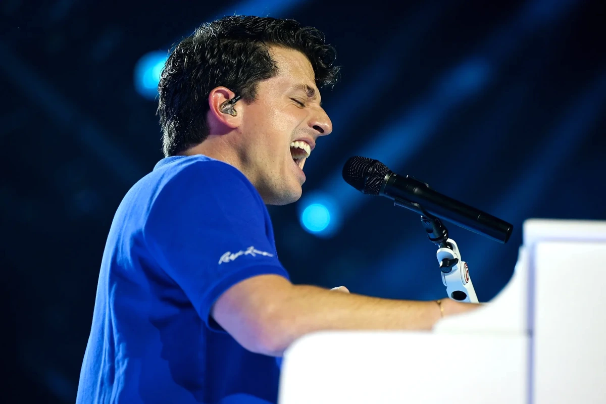 Charlie Puth sur scène, micro en main, éclairages de concert en arrière-plan, l’air fatigué