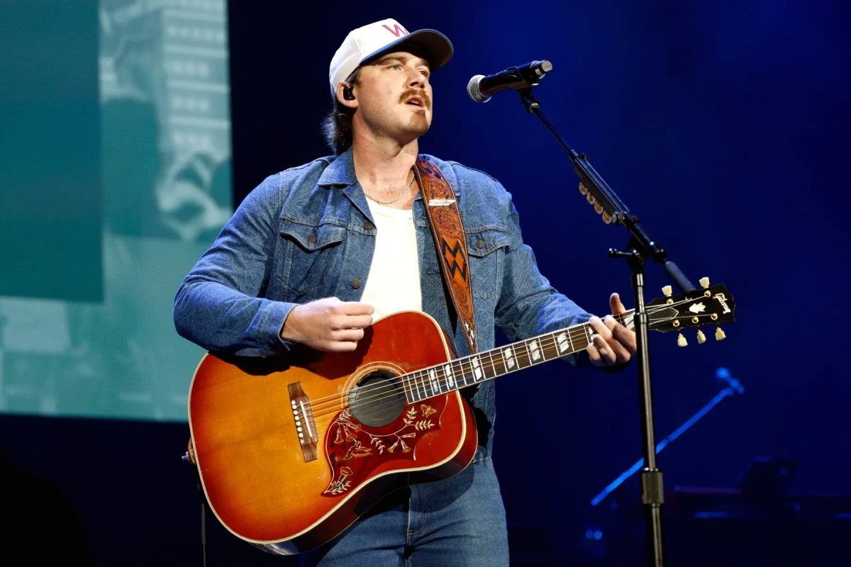 Morgan Wallen sur scène avec micro, éclairages de concert et foule, ciel sombre menaçant au-dessus de Pittsburgh